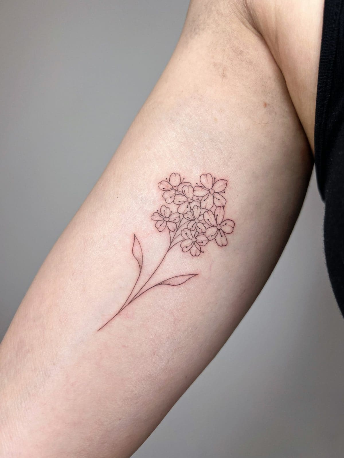 Bouquet de petites fleurs en fine line sur l'intérieur du bras
